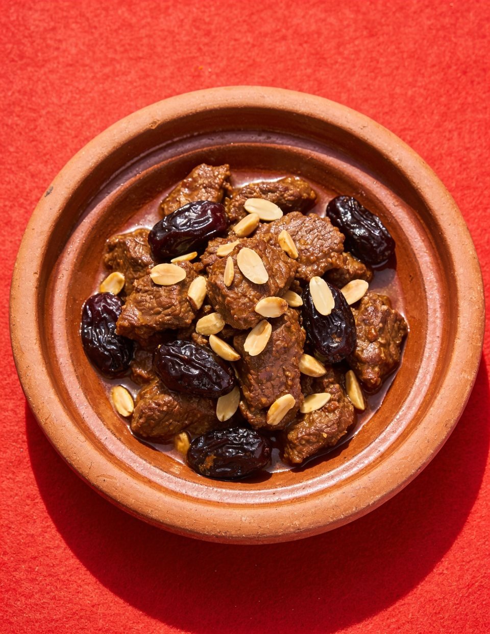Moroccan beef tagine with prunes and almonds in a clay dish